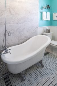 Claw foot tub with chrome fixtures and black and white marble tile floor and marble wall by Owings Brothers Contracting.