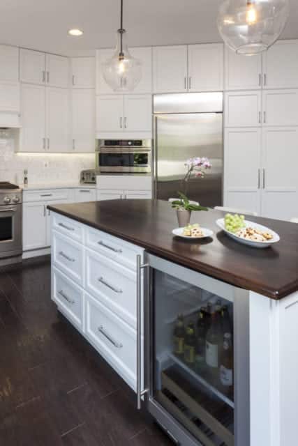 white kitchen island cabinet with custom wood counter top and beverage cooler