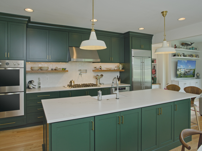 kitchen with green cabinets on perimeter and island, white counter tops and goldtone hardware