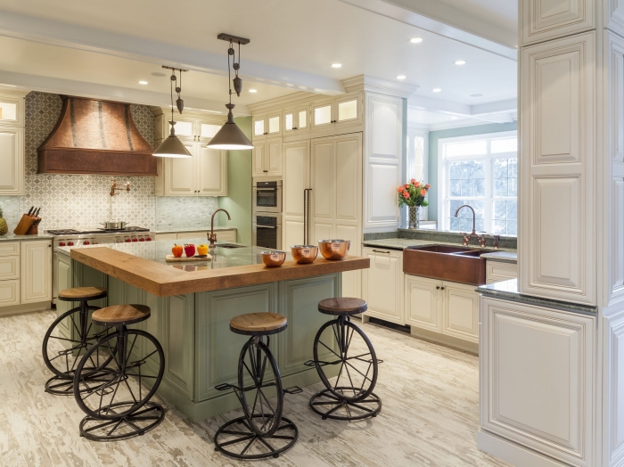 kitchen with cream cabinets with green engineered stone top and green painted island with wood counter top and white distressed wood floor
