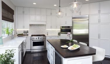 white kitchen with dark wood countertop and soft white marble backsplash and natural wood floorshit
