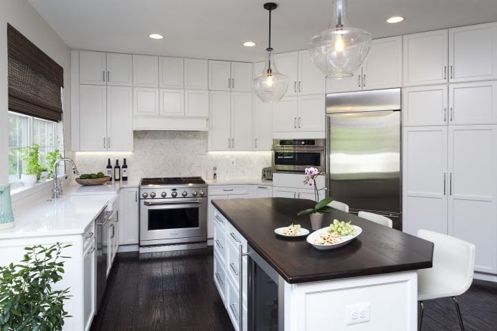 white kitchen with dark wood countertop and soft white marble backsplash and natural wood floorshit