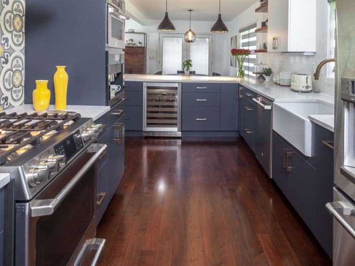 contemporary kitchen remodel with blue cabinets, white engineered stone countertops white backsplash focal point backsplash of gray, white and yellow