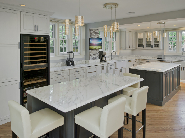 transitional kitchen with light and dark gray cabinets and carrera marble counter tops double island