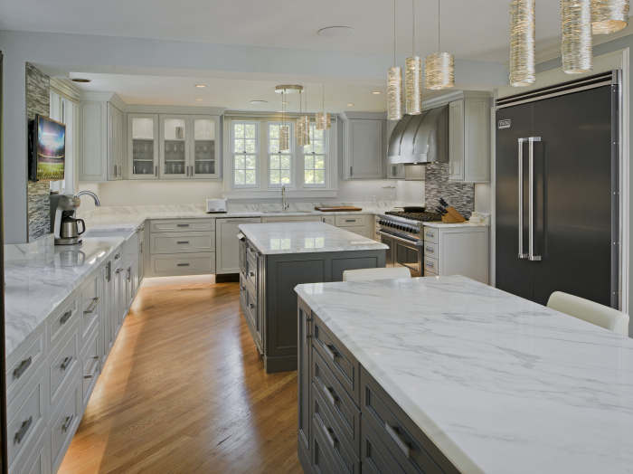 double island kitchen with gray cabinets and marble counter tops, commercial stainless appliances , lighted toe kick