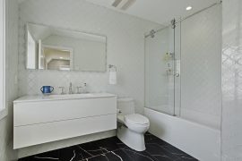 contemporary bathroom with modern white wall tiles, a glass shower and tub enclosure, and black flooring
