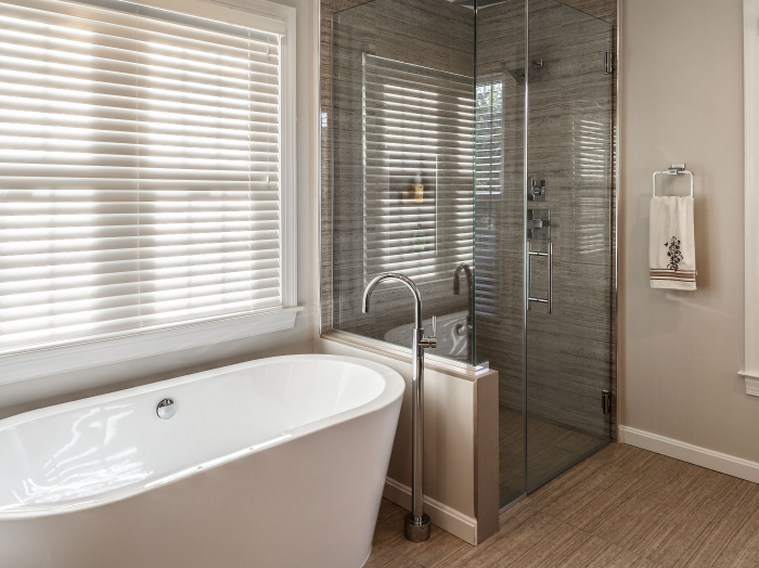 wood look tile glass enclosed shower with large tile floor and freestanding soaking tub