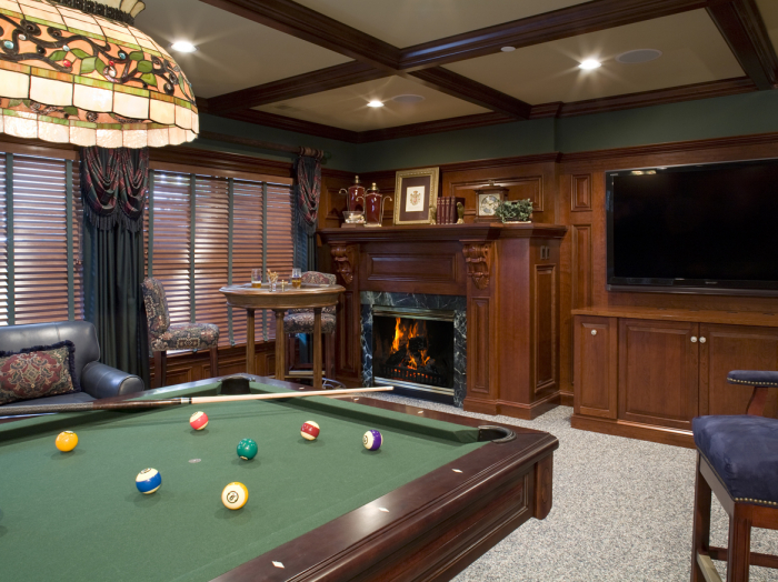 dark wood paneled game room with wood beam trim on ceiling