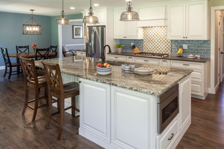 Newly remodeled kitchen with large seated island and blue tile backsplash with patterned focal point