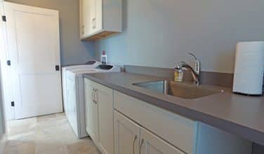 laundry room with cabinets, folding counter, fold away ironing board and sink