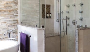 master shower with multiple sprays, shower heads, bench and pebble floor