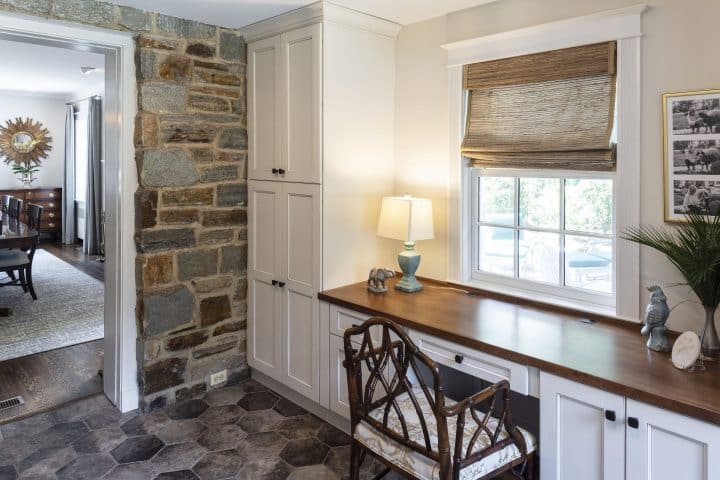 new mudroom bump out with floor to ceiling painted cabinetry, stone and slate, a stained wood built- in desk top