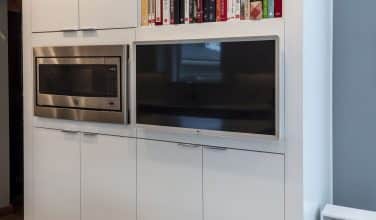 white painted cabinets with chrome pulls and built in TV and microwave