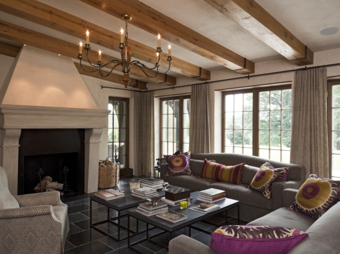 castle-like living area with chandelier, large fireplace, and wood beams