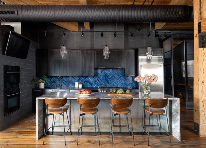 black cabinetry, blue backsplash, light granite waterfall island