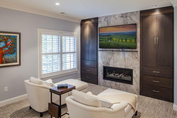modern fireplace in master bedroom seating area with floor to ceiling cabinetry