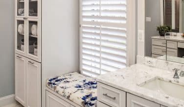 custom upholstered window seat between white painted cabinets