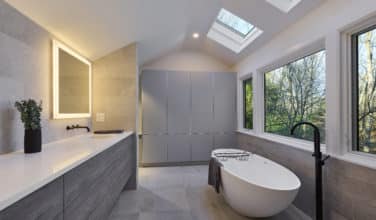 soft gray tile and wood primary bathroom with soaking tub