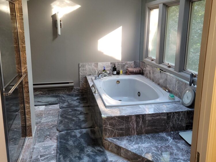 soft gray tile and wood primary bathroom with soaking tub